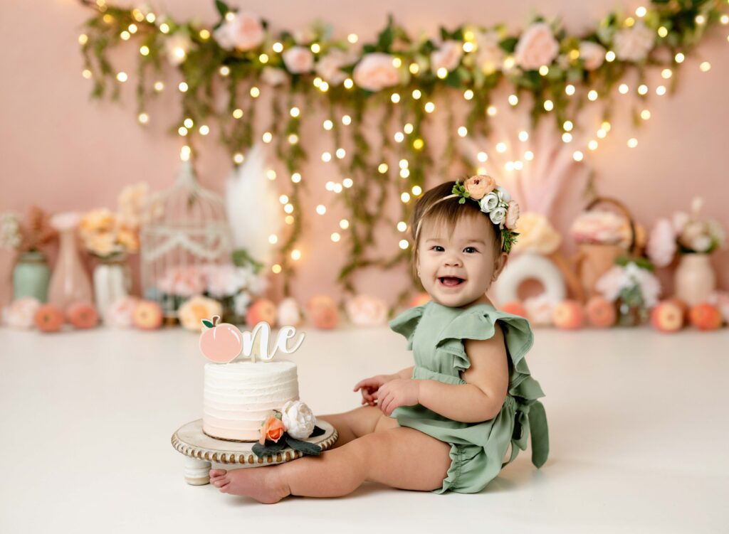 Baby girl eating cake and smiling for her sweet as a peach birthday photos.