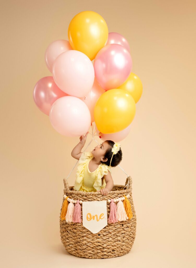 Baby in basket touching balloons