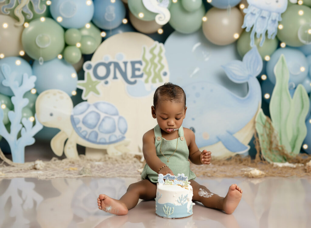 under the sea cake smash set with baby boy eating his birthday cake.