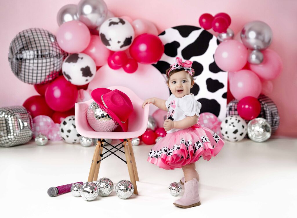 Baby girl in cowgirl outfit taking 1st birthday photos.