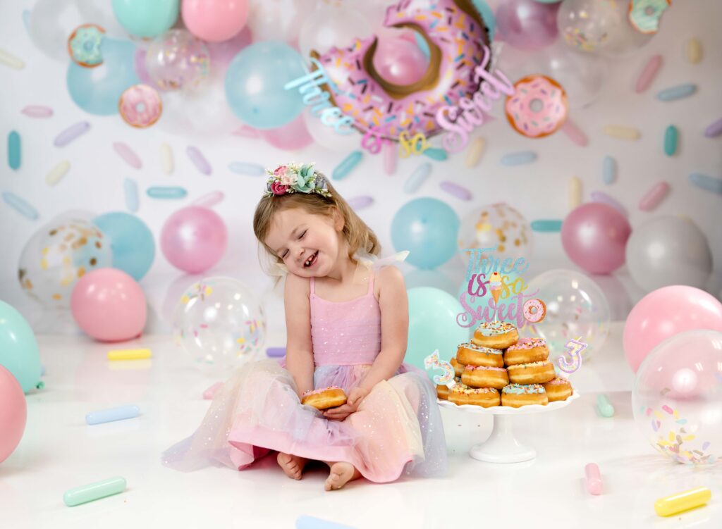 Toddler girl laughing and eating a donut,