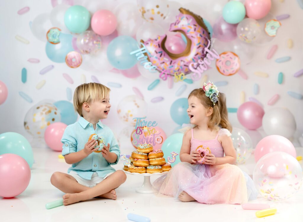 Twins eating donuts and laughing at each other.