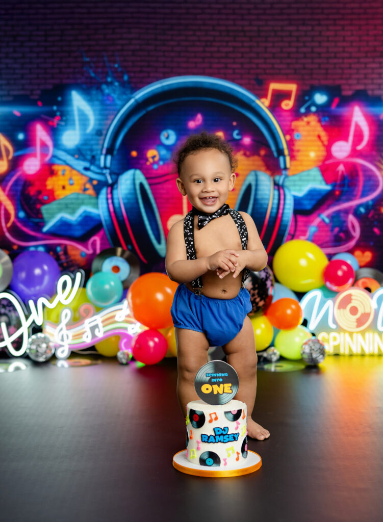 Boy standing in front of cake on DJ cake smash set photographed in Atlanta.