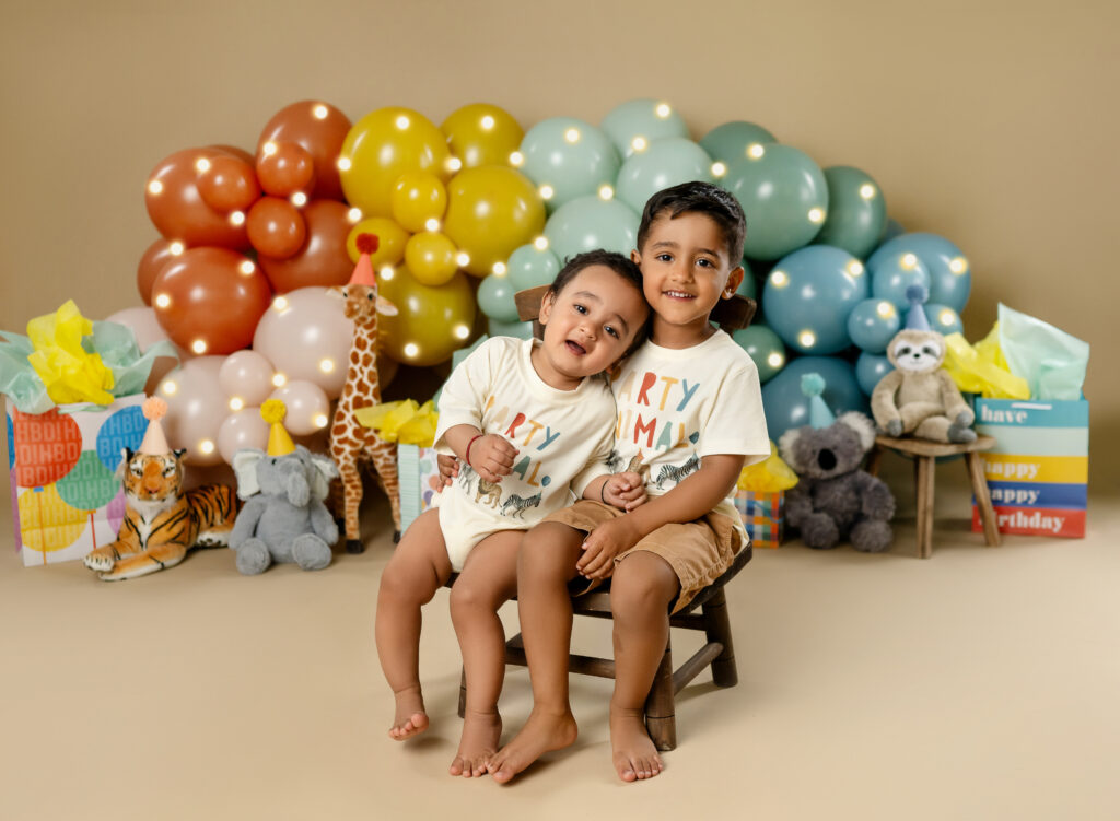 1 and 3 year old brothers hugging and taking birthday photos at Atlanta photo studio on a party animal birthday set.