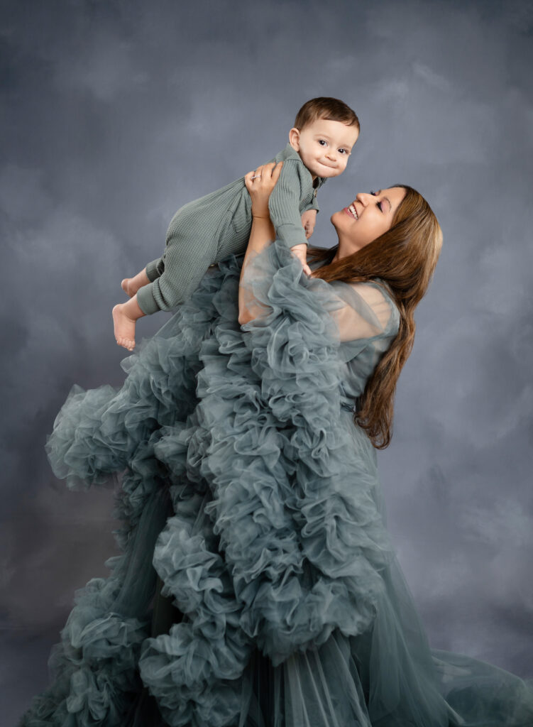 Mom holding baby up in the air and smiling at him.