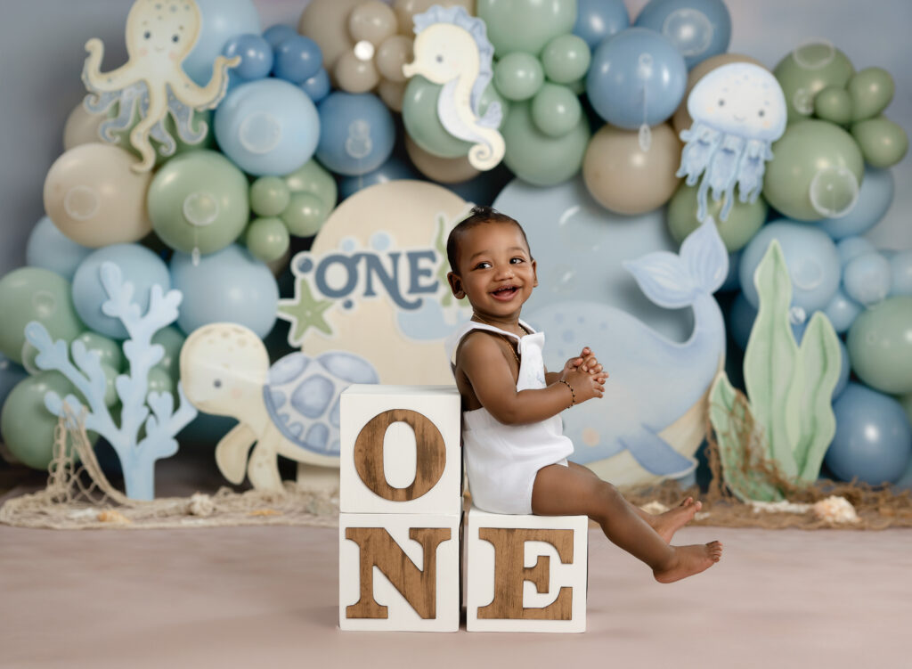 Baby boy taking 1st birthday photos on an under the sea cake smash set.