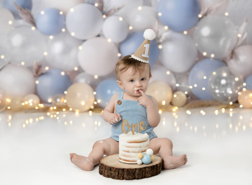 Baby boy in blue romper eating cake. Atlanta cake smash photo studio.