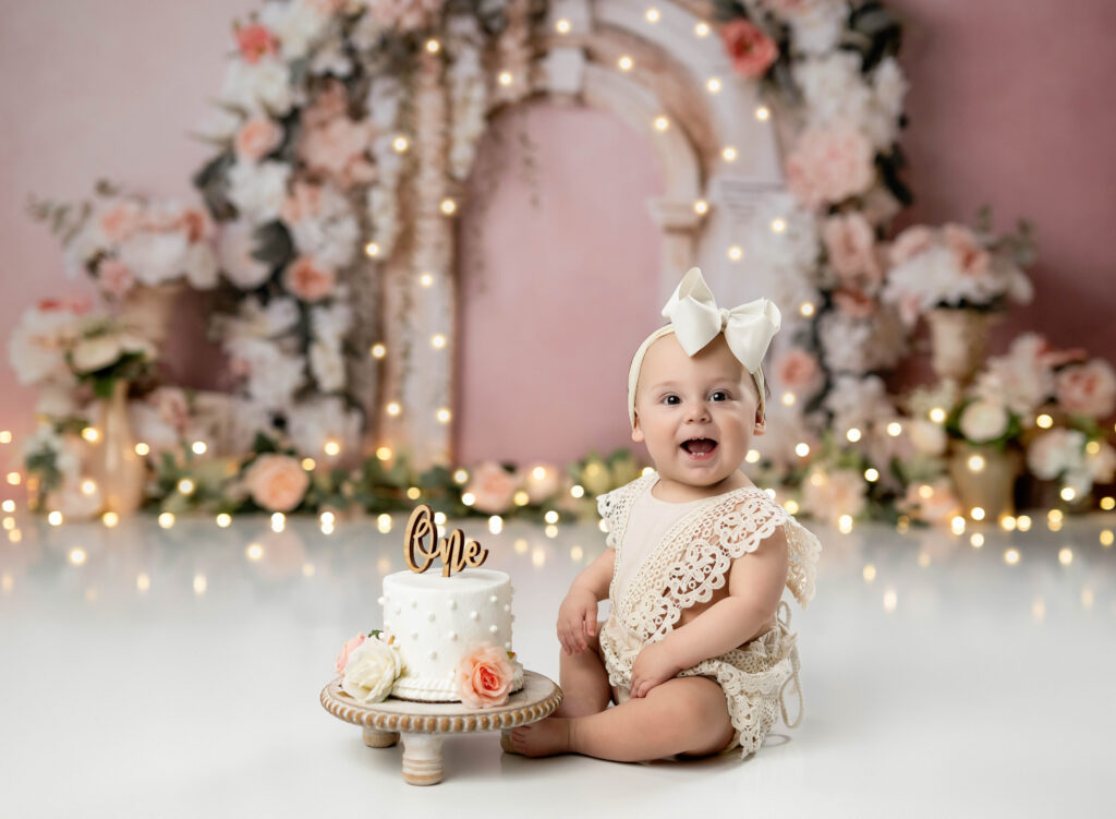 Cake smash photo of baby girl eating cake on floral arch backdrop