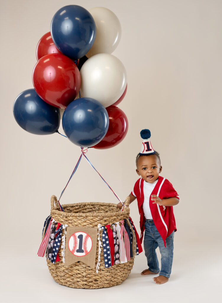 Boy standing next to a baseball theme balloon basket.