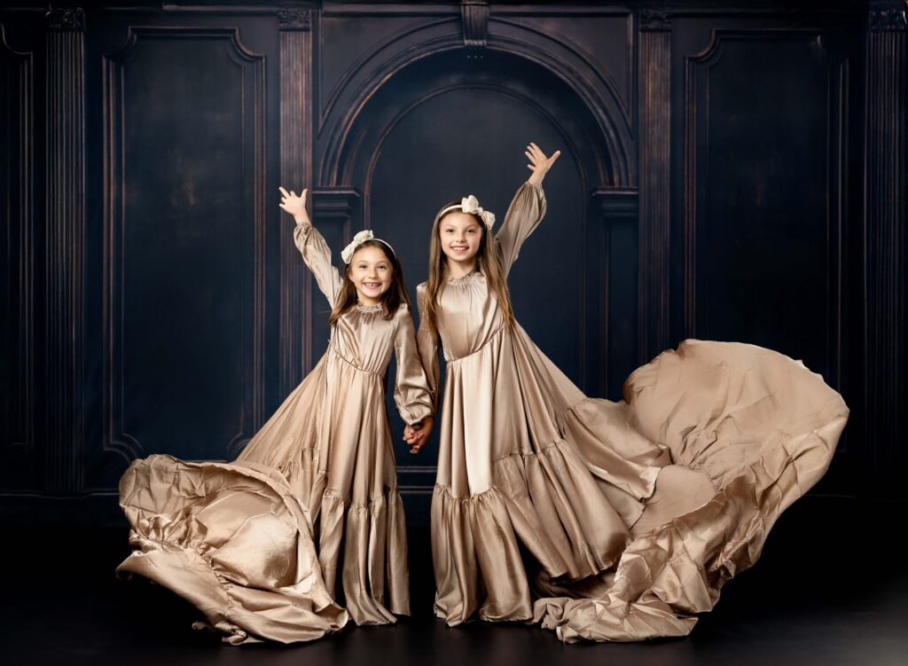 Girls standing together and tossing their long gowns in the air.