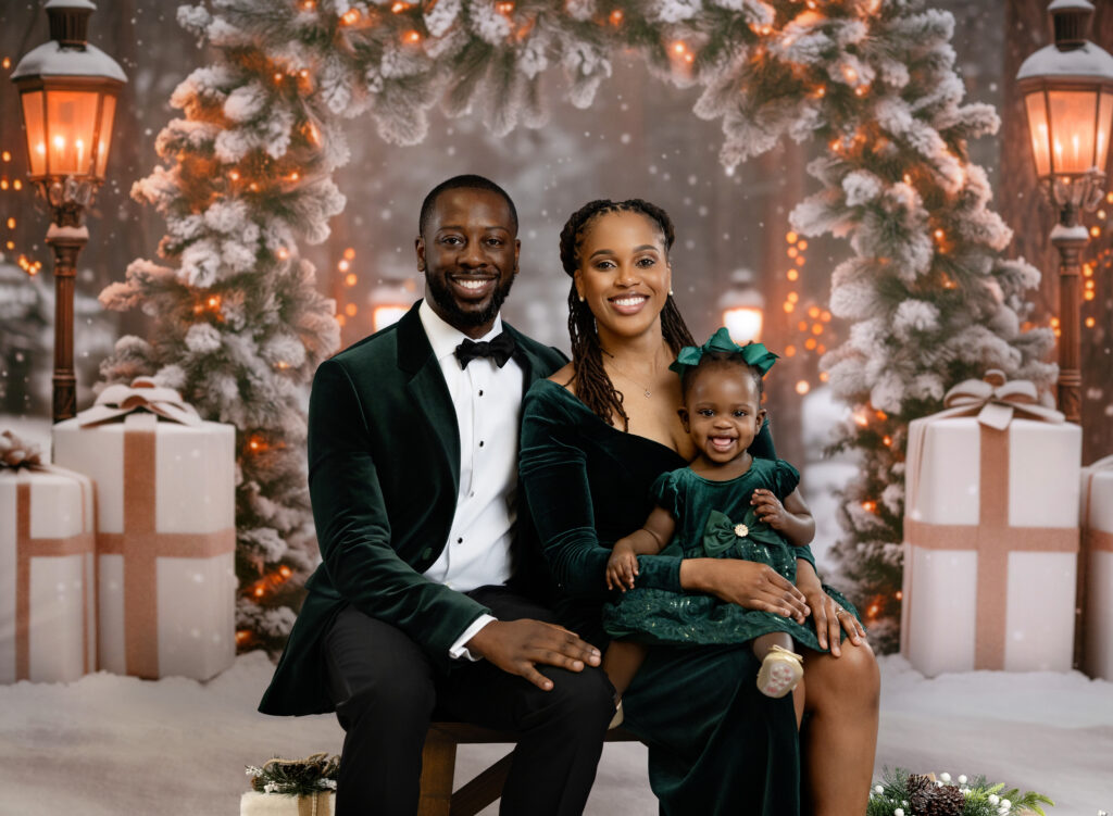 Mom, Dad and baby girl dress in green taking holidays photos in studio.