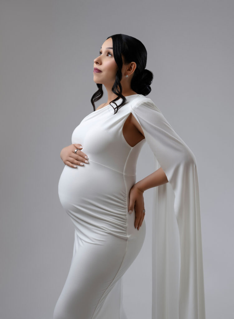 Pregnant women in white dress and holding belly bump.