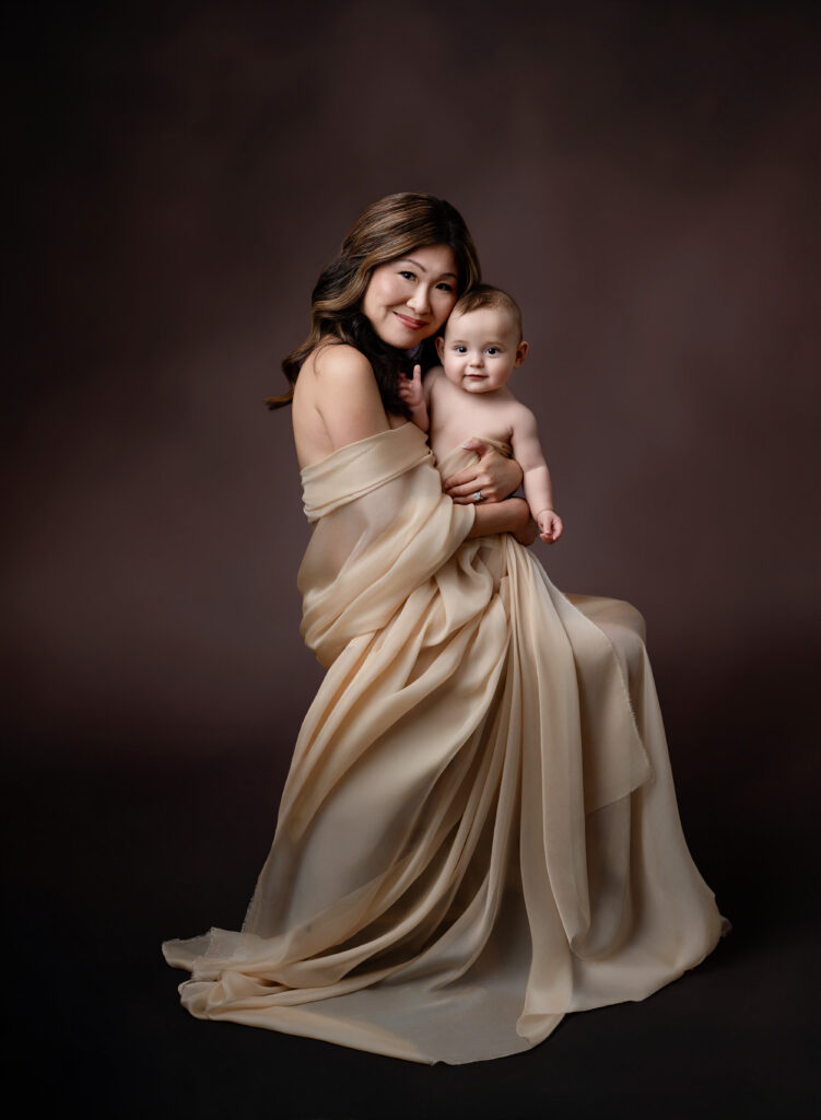 Mom draped in cream wrap and snuggling in with baby boy lovingly.