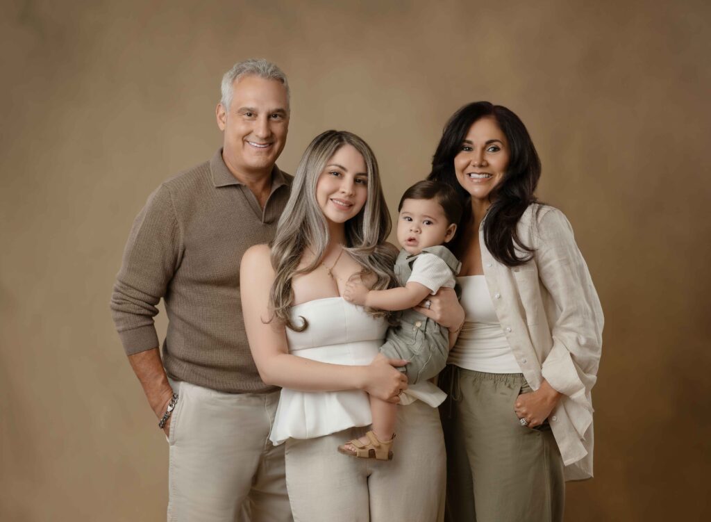 Mom hold baby with grandparents on each side, taking a family portrait at Atlanta photo studio.