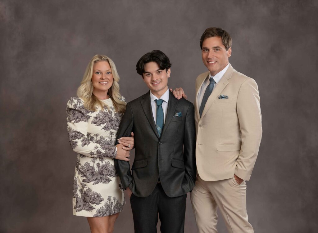 Mom and Dad on each side of their adult son taking a formal family portrait at Atlanta Family photo studio.