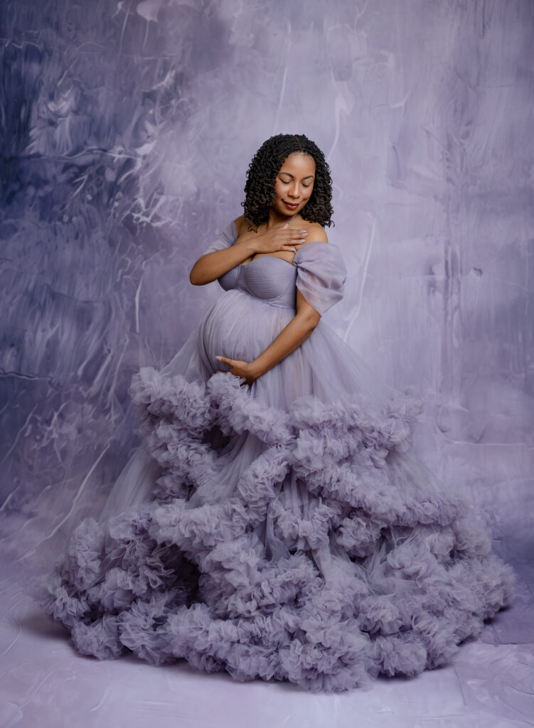 Mom in lavender maternity dress on purple backdrop. Atlanta Maternity Photography.