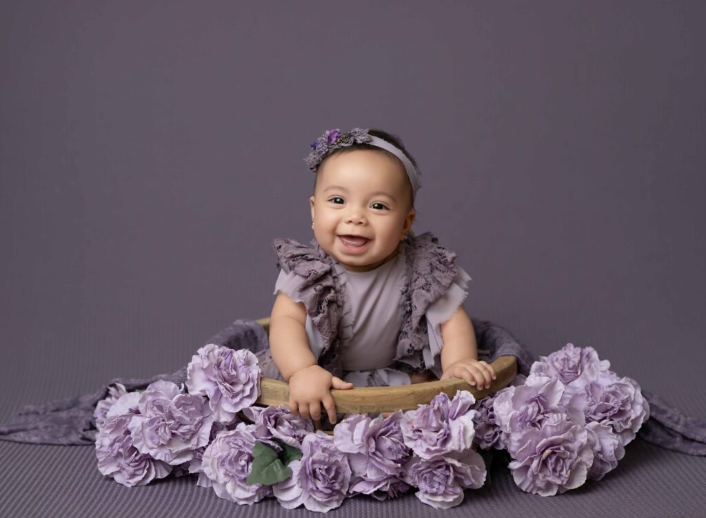 Baby girl sitting in a wooden bowl that is layered with lavender florals.