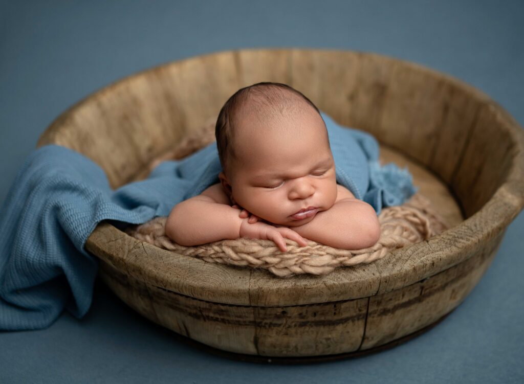 baby sleeping on their arms in a wooden rustic bowl.