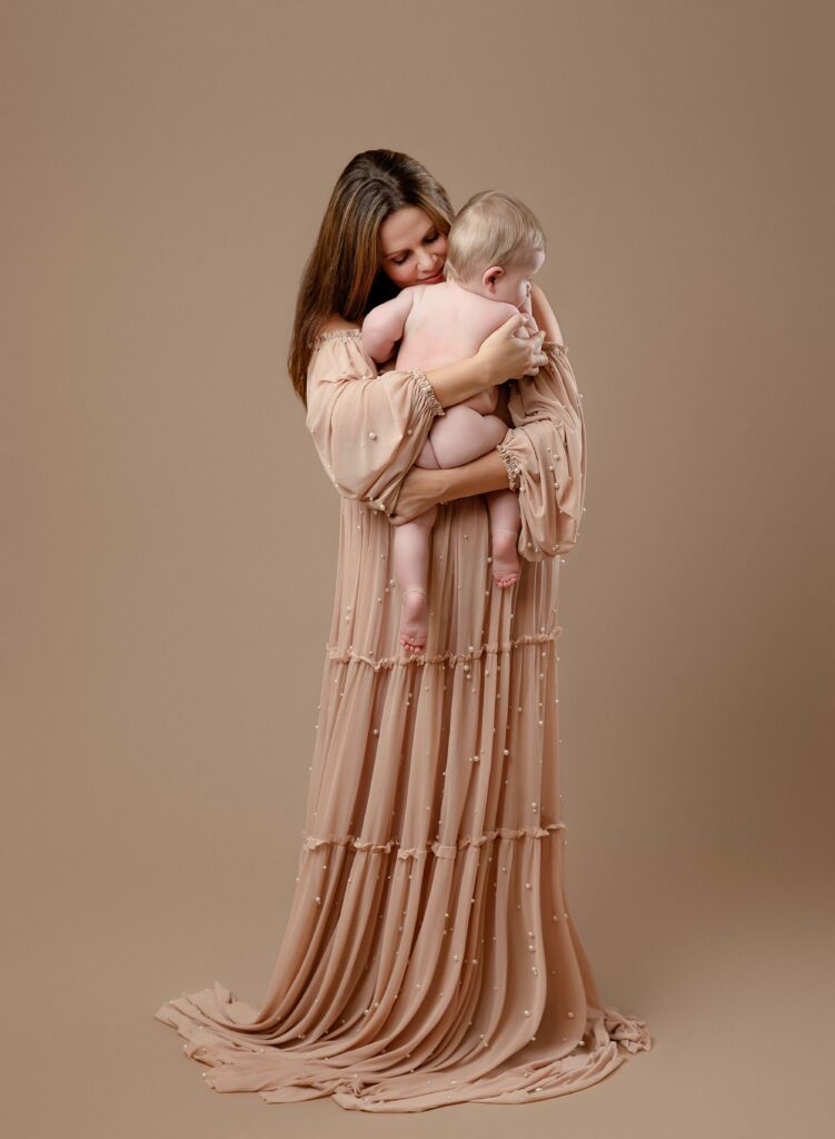 Mother cuddling her naked baby boy in her arms.