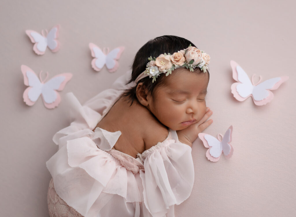 Baby sleeping on belly with pink butterflies around them.