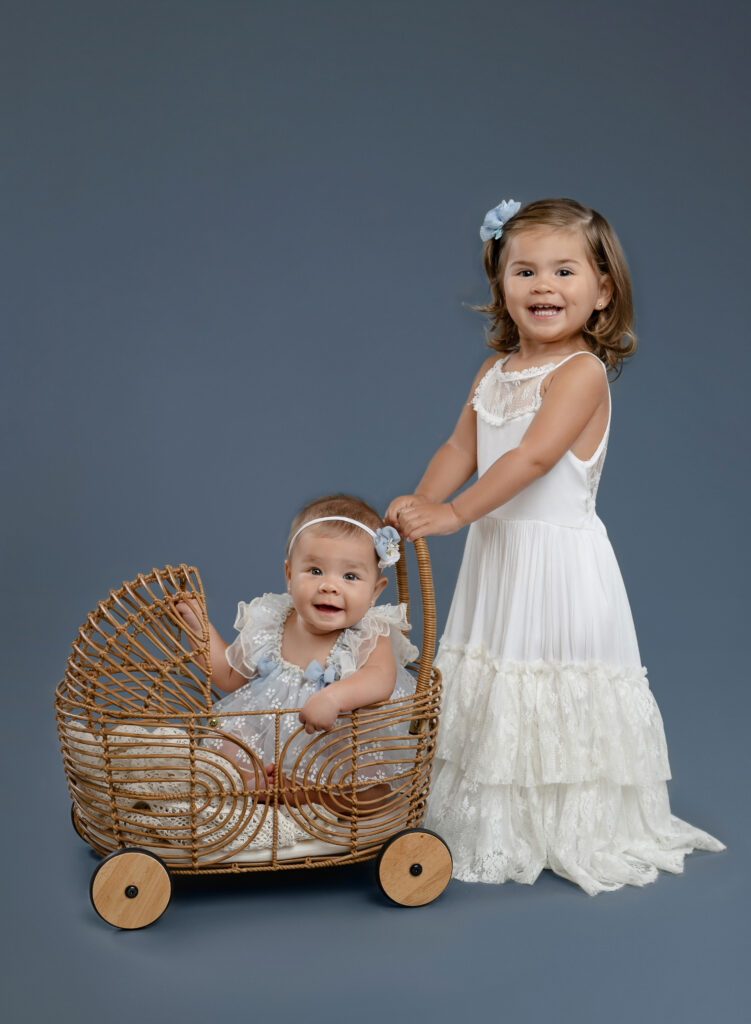 Baby in bamboo carriage and sibling pushing it.