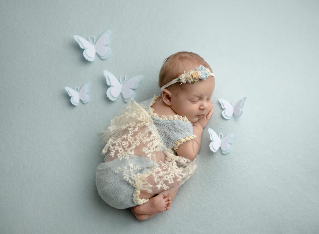 Baby sleeping on their belly with felted butterflies around them.