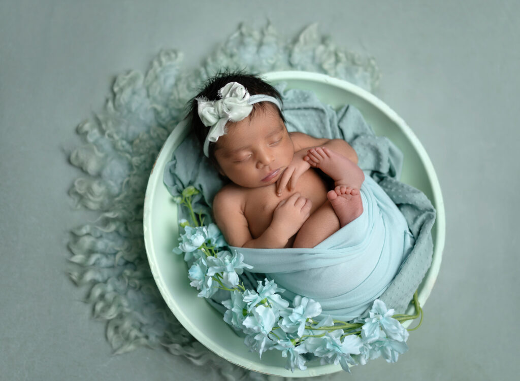 Baby girl sleeping in mint bowl with florals.