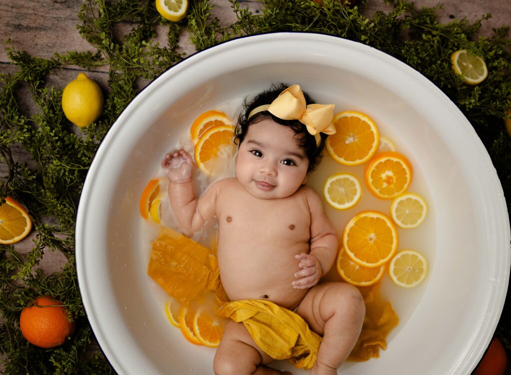 Baby girl laying in tub filled with fresh fruit. photo taken by jenni Nikki photography at Woodstock-Atlanta photo studio.