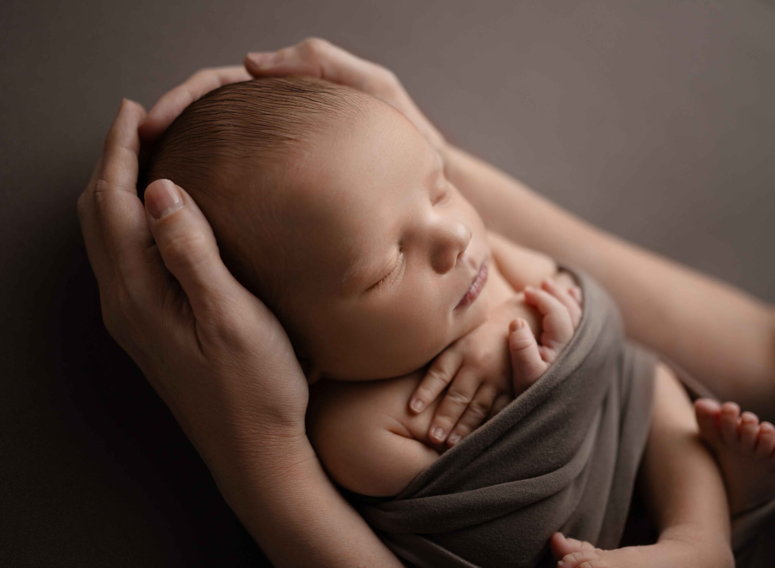 Baby cradled in Mom's hand sleeping peacefully.