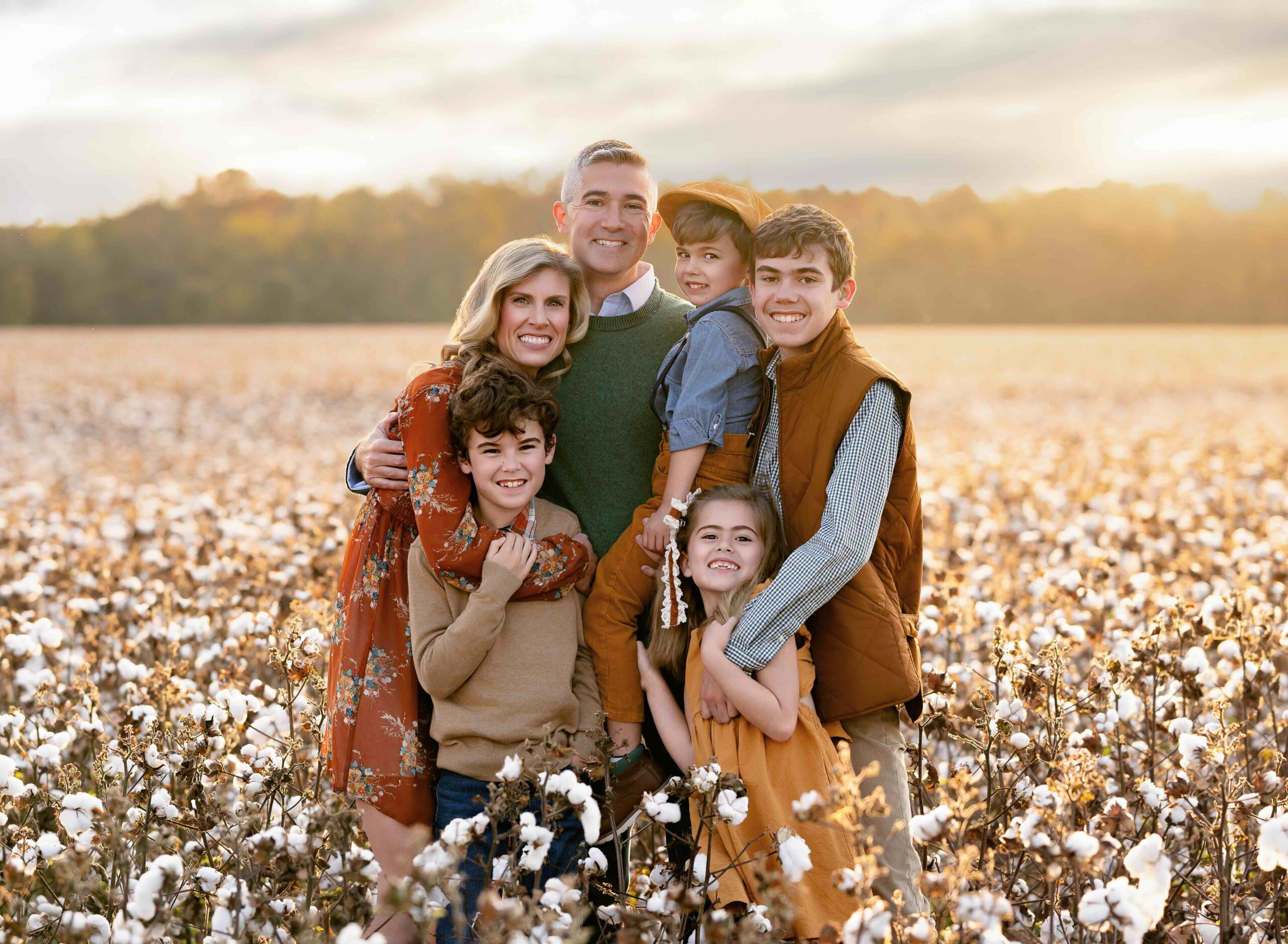 Family snuggling and smiling in cotton field in Georgia.