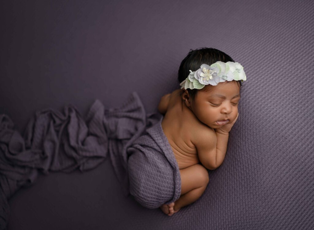 baby sleeping on tummy with a purple wrap around their bum 