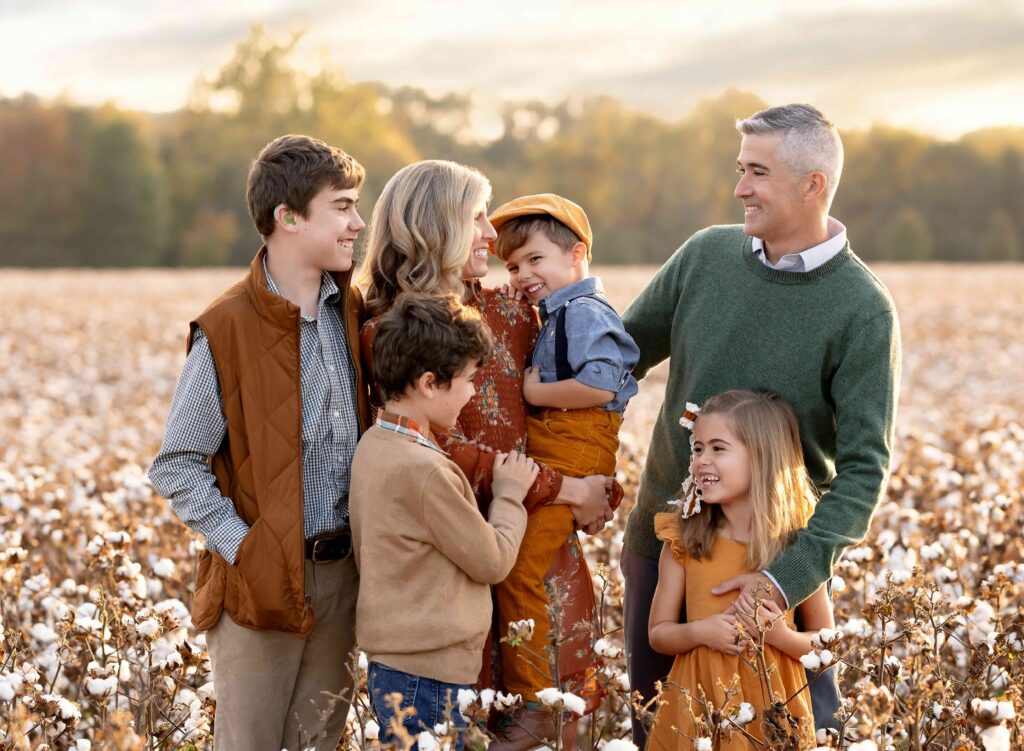 Mom, Dad and 4 kids laughing in a cotton field.