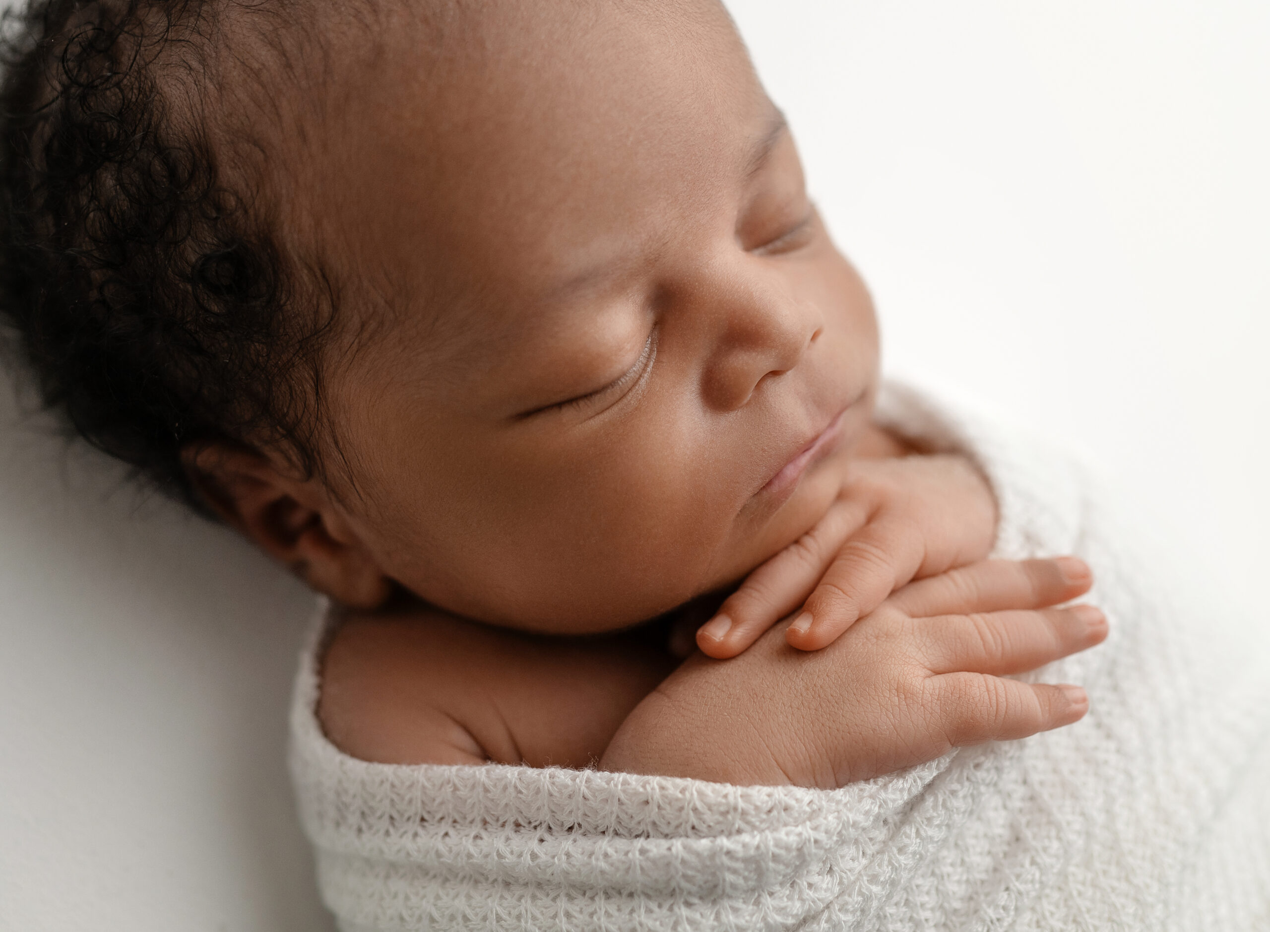 Newborn baby boy sleeping and swaddled in white wrap for his Atlanta Newborn photoshoot.
