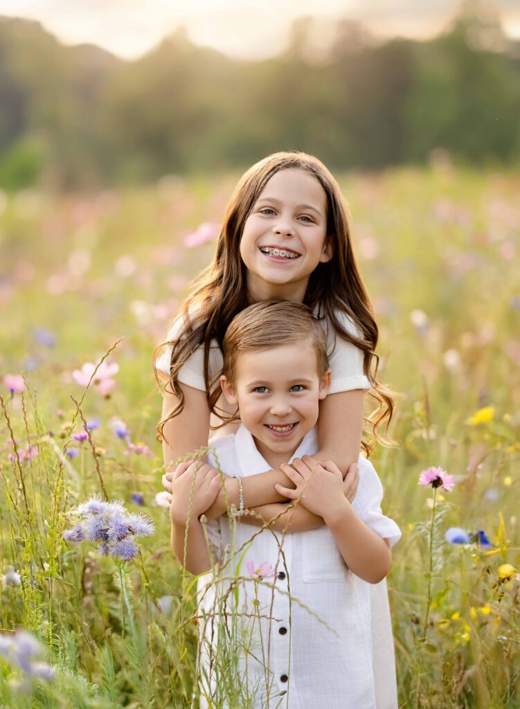 siblings hugging in wildflower field near Atlanta GA.