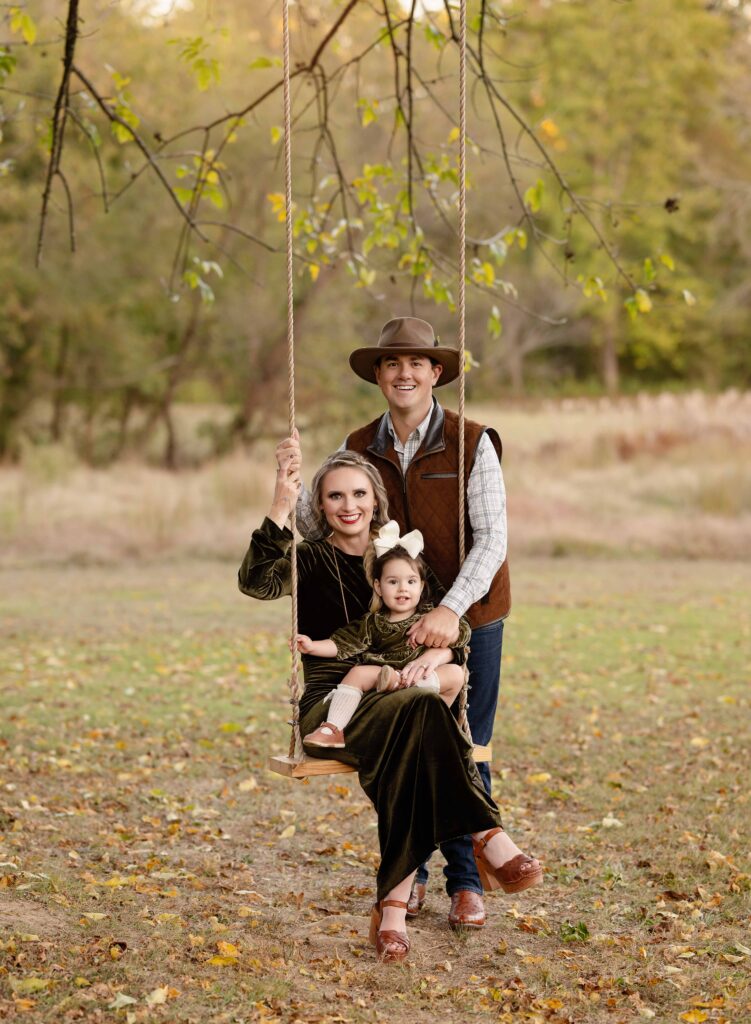 Family sitting on tree swing taking portraits by Atlanta family photographer.