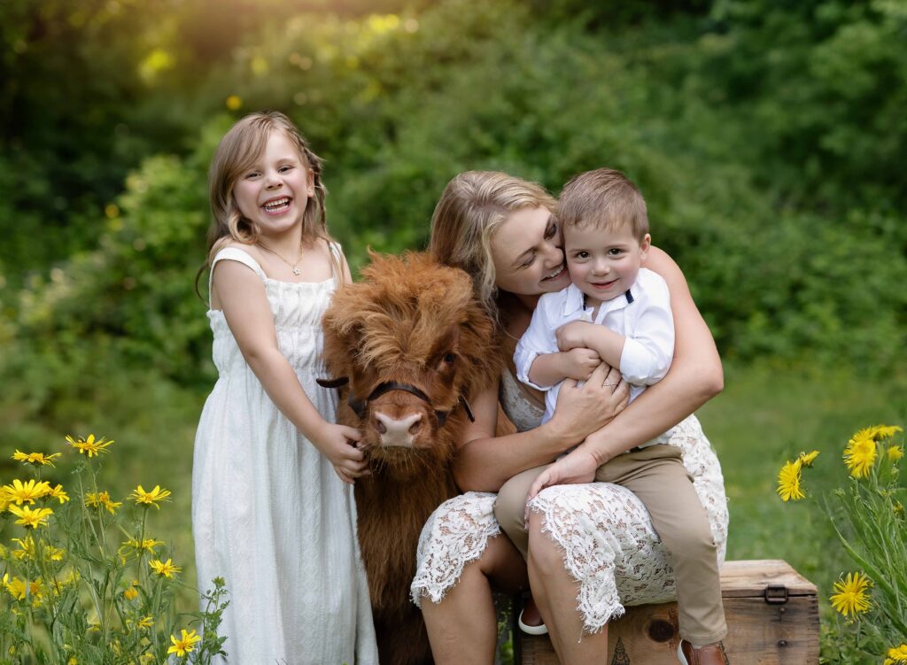 Mom and kids taking photos with a baby highland cow.