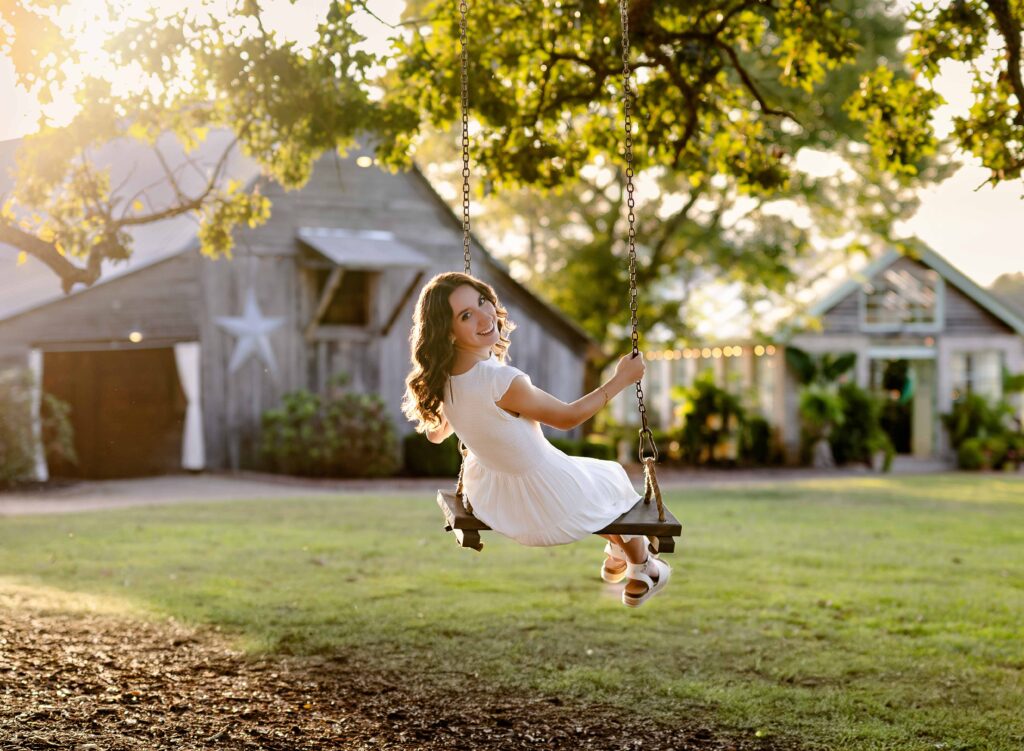Teen in tree swing, looking over her shoulder at the camera.