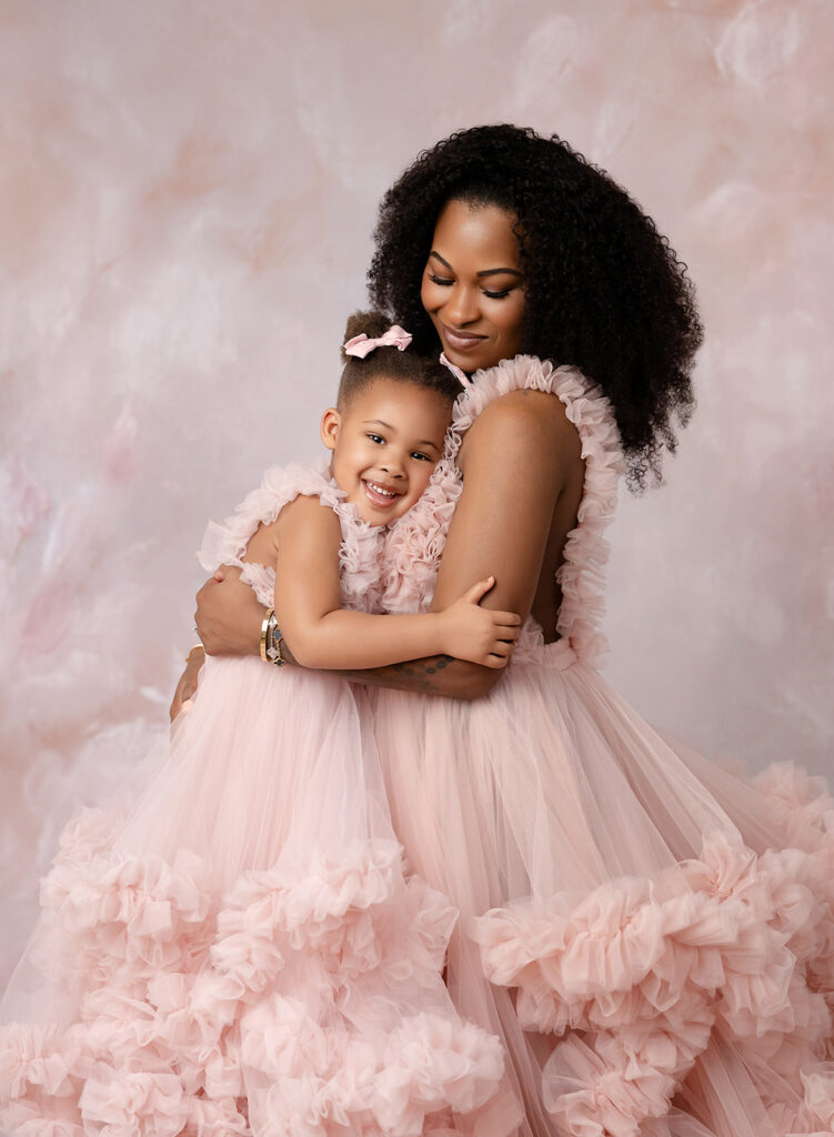 Mother and daughter in pink gown snuggling.