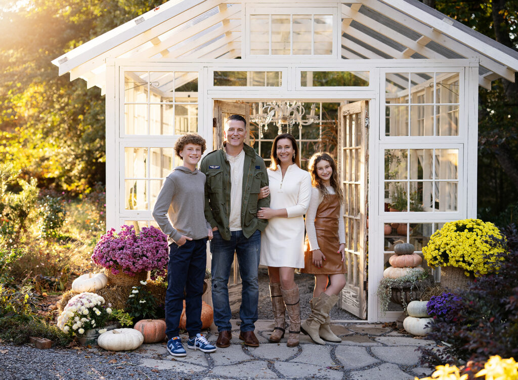 Family being photographed in front of a white glass greenhouse.
