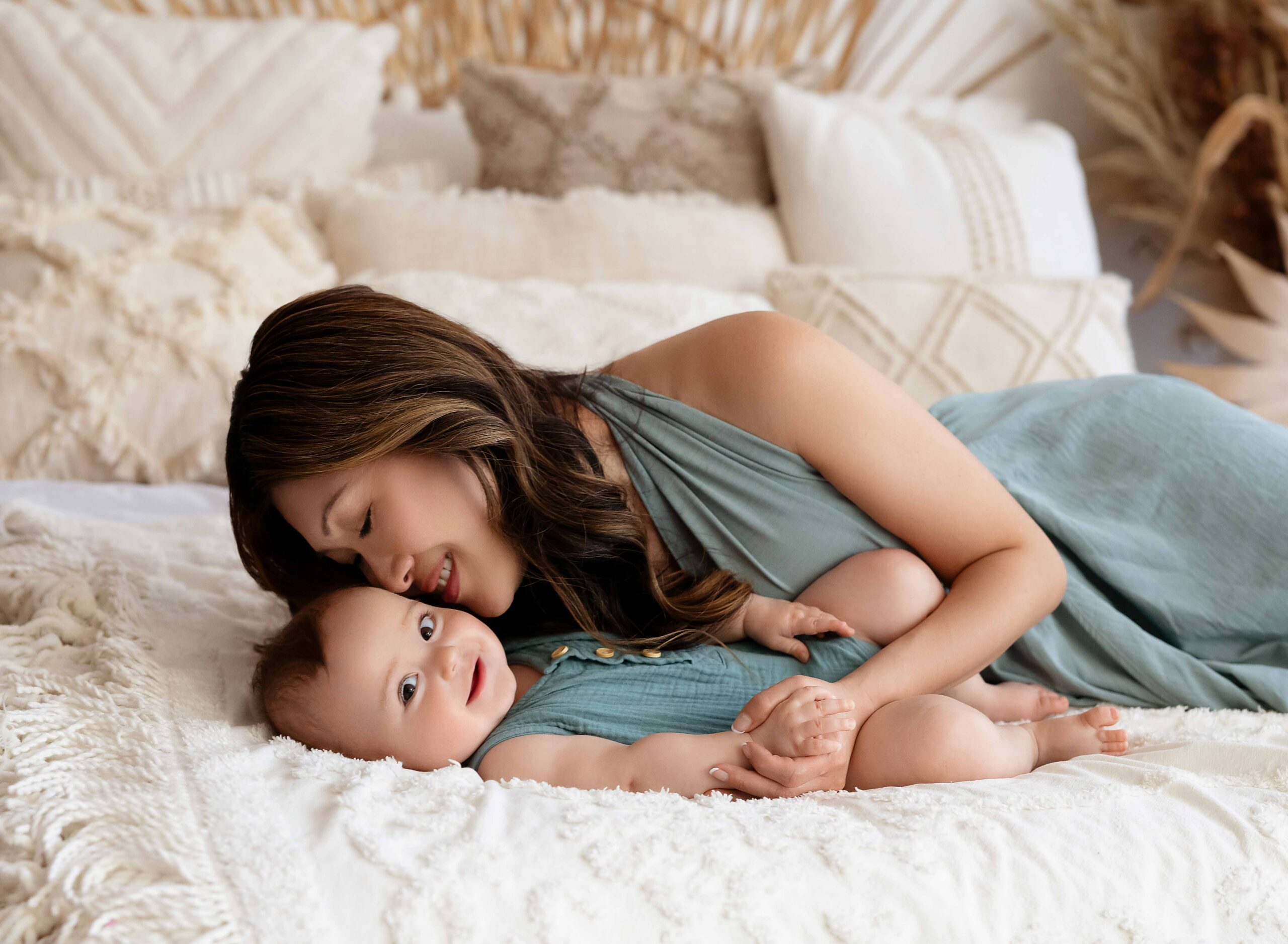 Mother lying with baby on bed during a lifestyle Atlanta motherhood photography session in a cozy studio setting.
