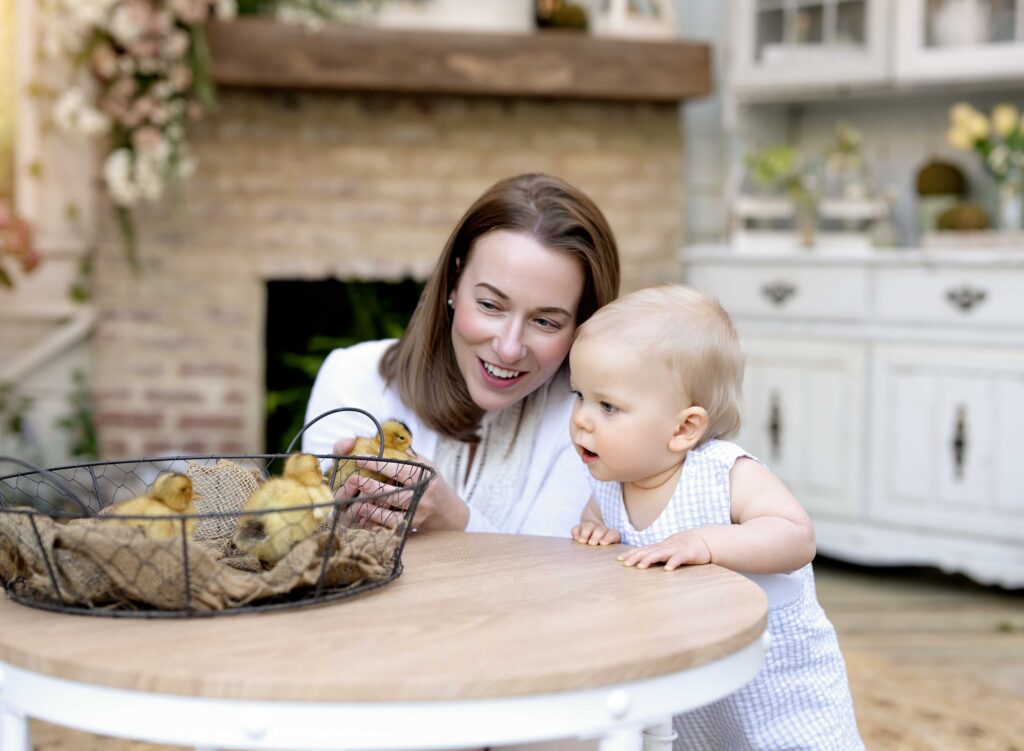 Mother and baby looking at baby ducklings during Atlanta Easter mini sessions in a cozy spring lifestyle photography studio.
